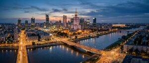 A professional, high-angle panoramic view of the Warsaw skyline at twilight, showcasing the iconic P